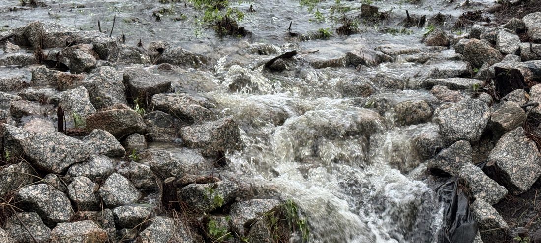 Stormwater rushing over riprap rocks after heavy rain